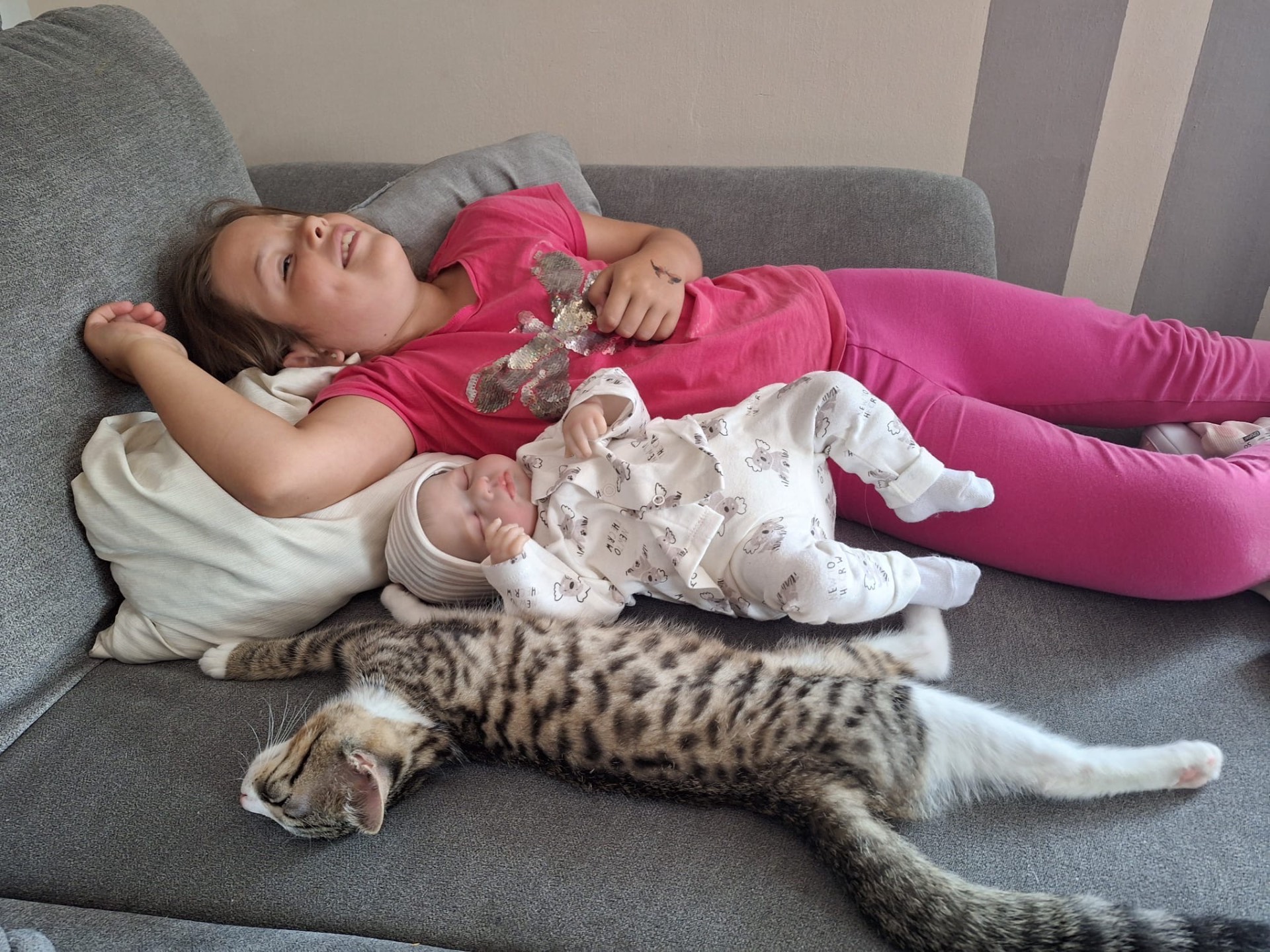 Kinder liegen mit Kater Sammy gemeinsam auf dem Sofa